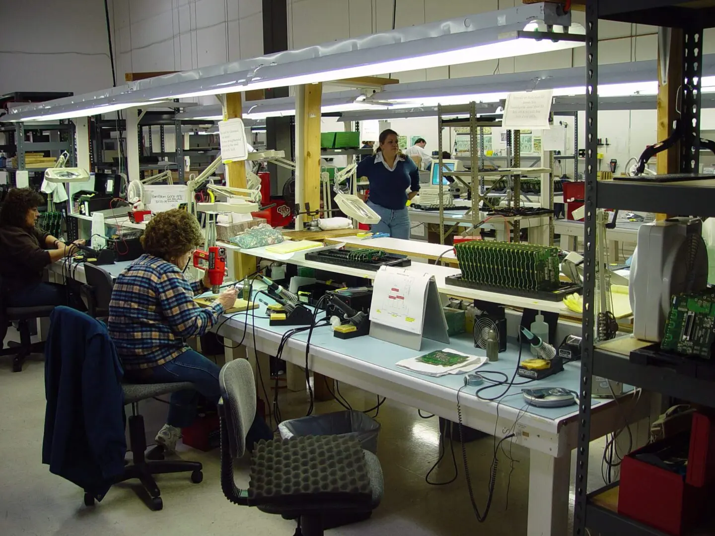 People working in a busy electronics assembly workshop.
