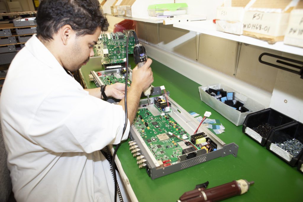 A man working on an electronic board in a lab.